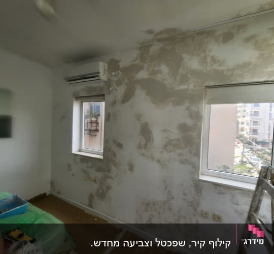 חדר עם קיר מוכן לצביעה, סולם וכלי עבודה
